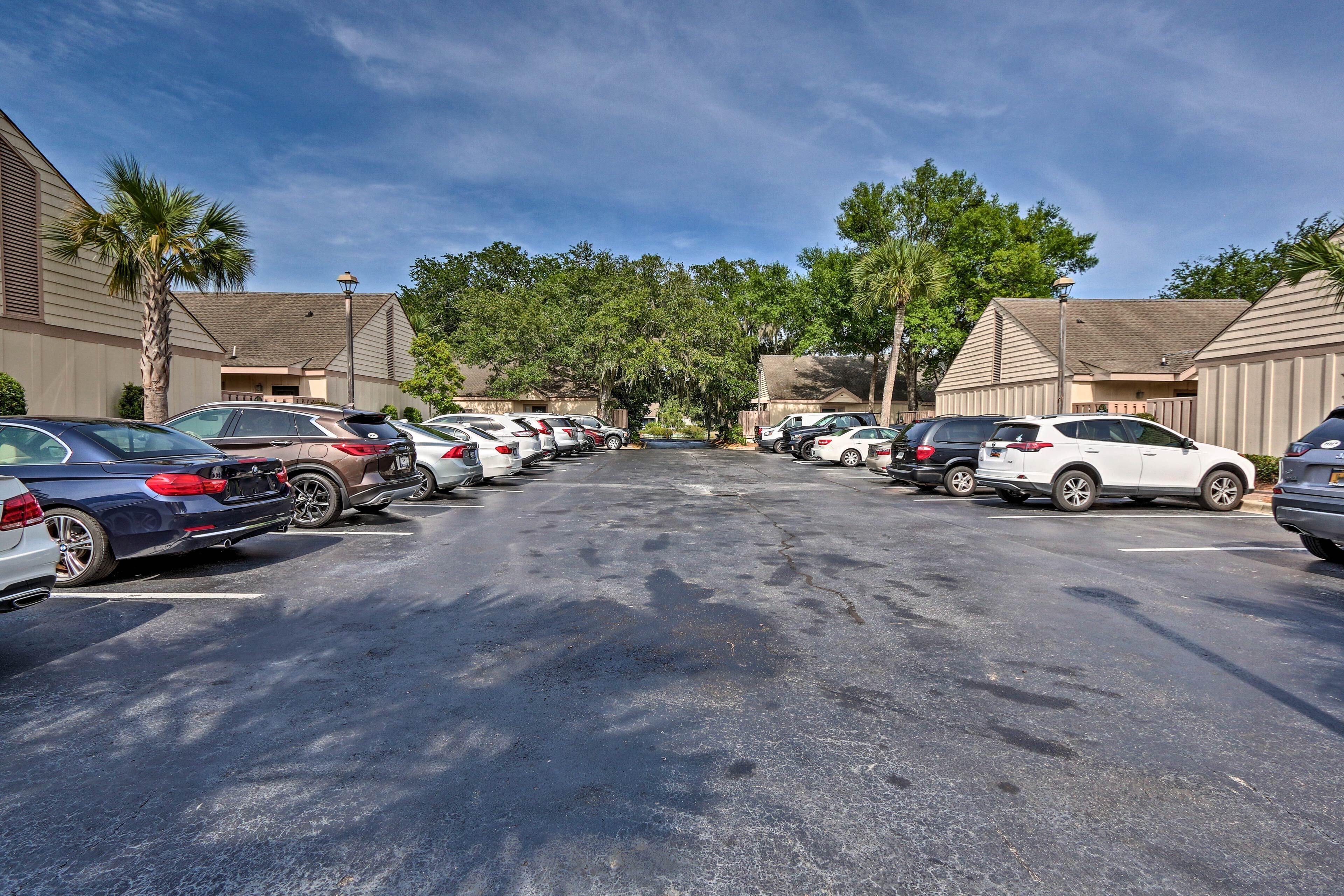 A parking lot with multiple cars and a row of buildings with a flat roof and beige siding.