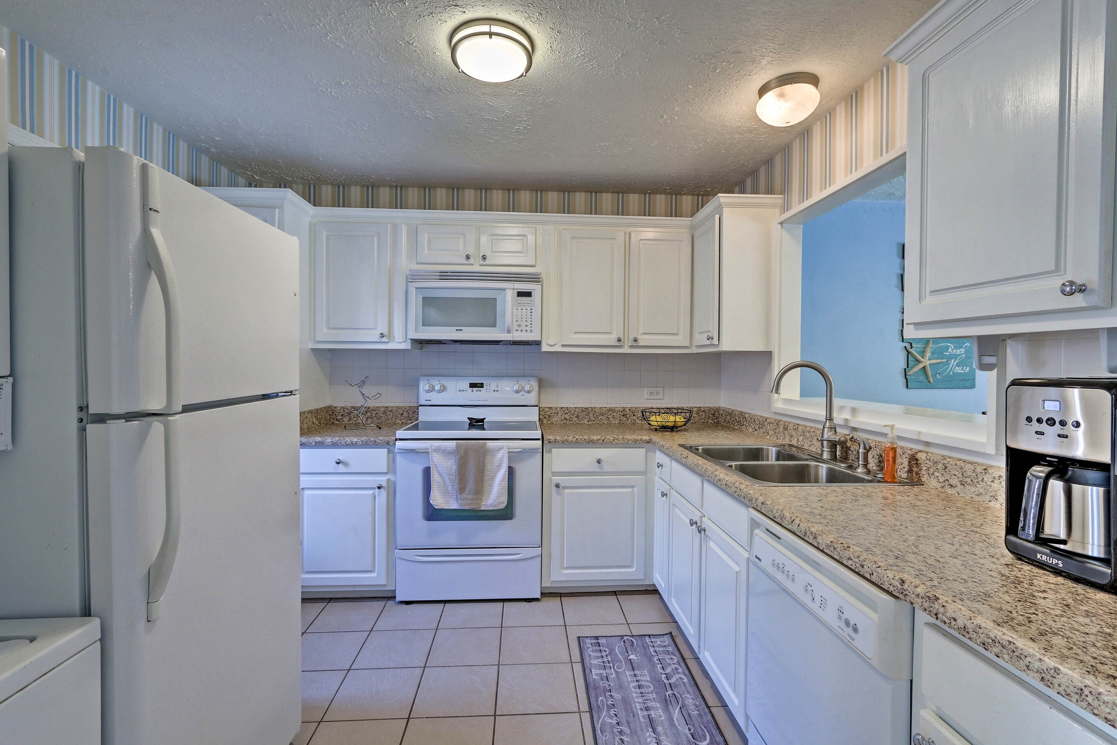 A kitchen with white cabinets, a microwave, an oven, a dishwasher, and a coffee maker.