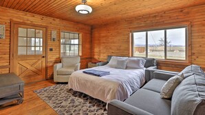 A log cabin bedroom with a bed, two chairs, a sofa, a window, and a wooden ceiling. - Secluded Cabin w/ Hot Tub, Game Room & Views! (Durango)
