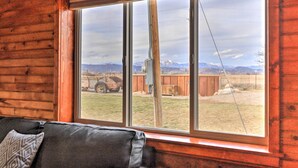 A room with a large window, wooden walls, and a black leather sofa with a patterned pillow. - Secluded Cabin w/ Hot Tub, Game Room & Views! (Durango)