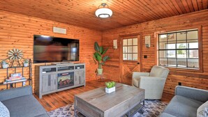 A cozy cabin interior with wooden walls, a flat-screen TV, a fireplace, and a comfortable seating area. - Secluded Cabin w/ Hot Tub, Game Room & Views! (Durango)