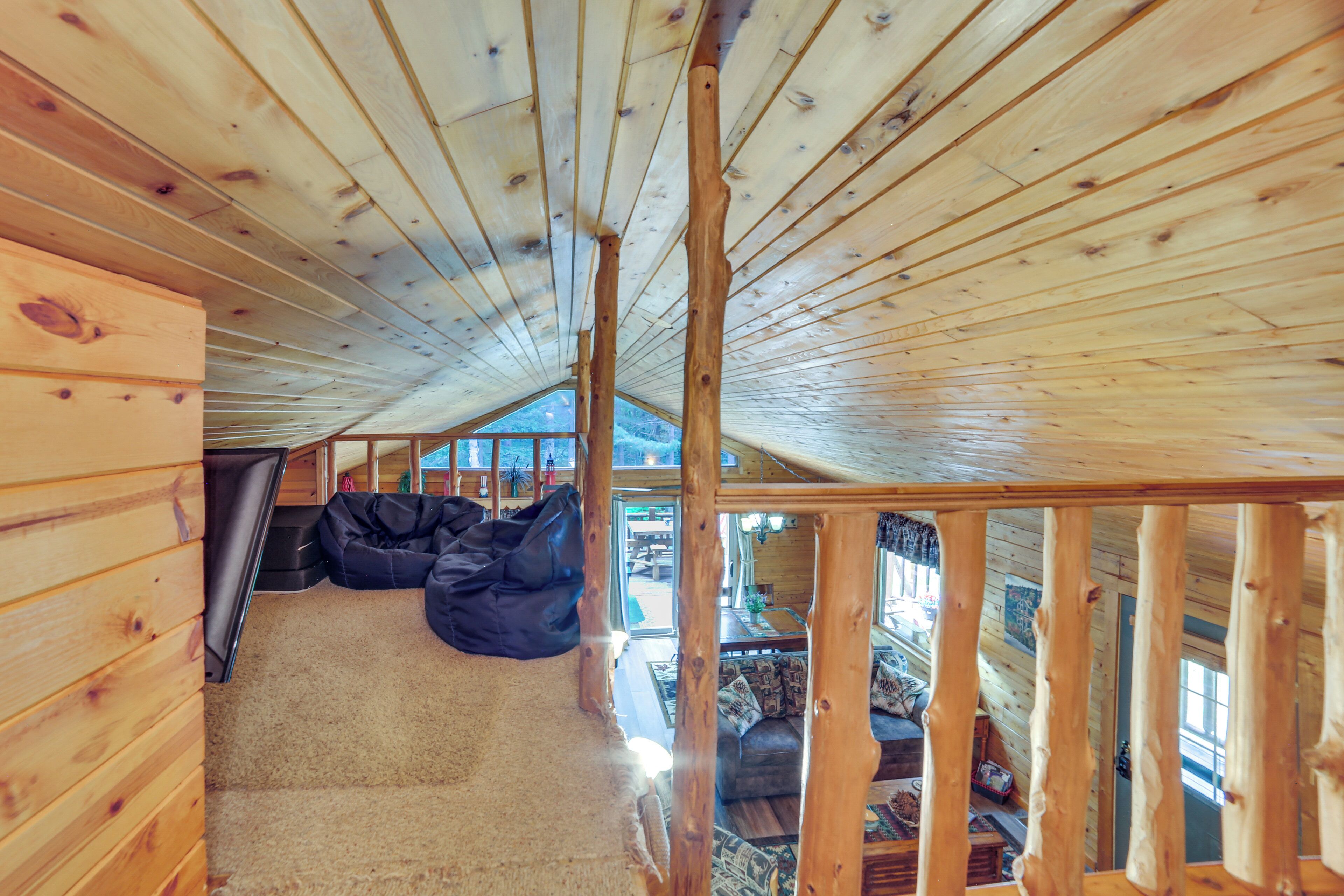Un interior de madera con techo inclinado, un sofá y vistas al exterior.