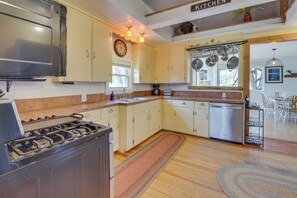 A kitchen with a stove, dishwasher, and a clock on the wall.