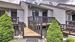 A two-story building with a wooden deck and a small staircase leading to the entrance. - Year-round Fun in Beech Mountain! Condo w/ Balcony (Banner Elk)
