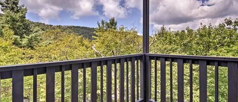 Une terrasse en bois offrant une vue sur une colline boisée.