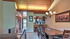 A dining area with a wooden table and chairs, a kitchen in the background, and a hallway leading to another room. - Year-round Fun in Beech Mountain! Condo w/ Balcony (Banner Elk)