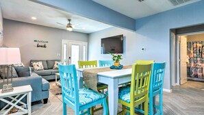 A dining area with a white table, blue and yellow chairs, and a ceiling fan. - Charming Coastal Getaway, Near Beach & Pier! (Gulfport)