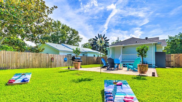 A backyard with a wooden fence, two blue chairs, a hammock, and a patio table. - Charming Coastal Getaway, Near Beach & Pier! (Gulfport)