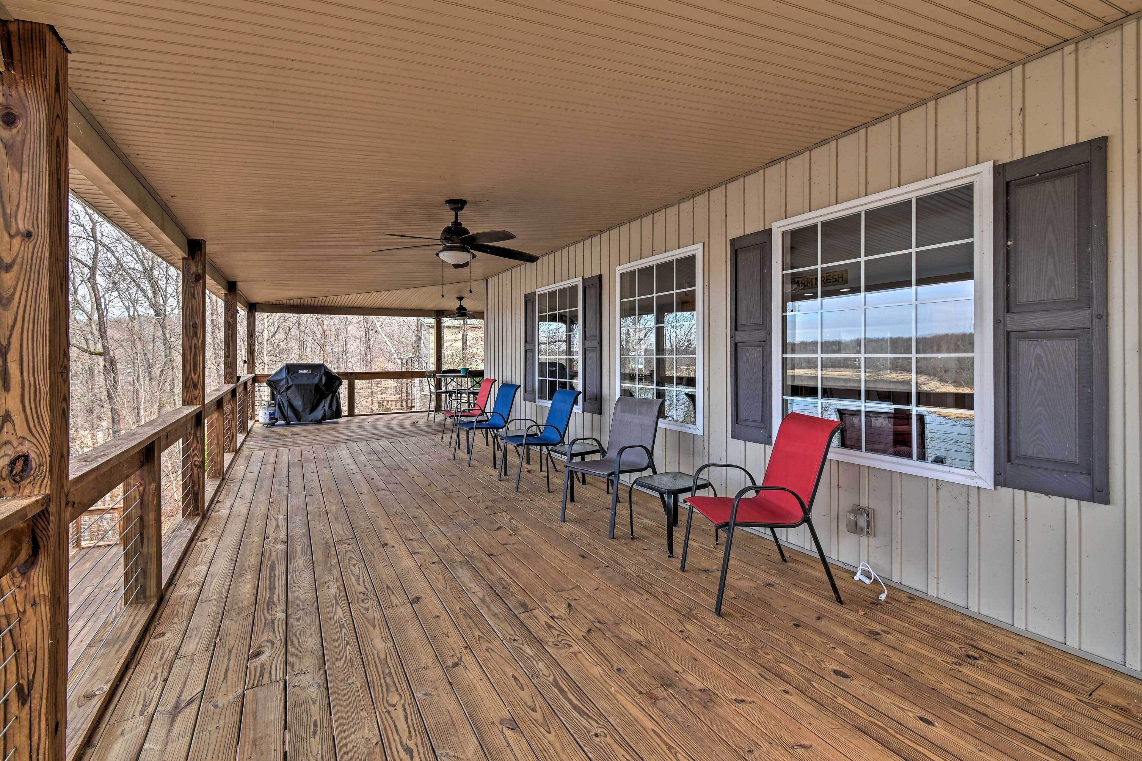 A covered porch with wooden flooring, a ceiling fan, and a row of chairs.