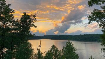 A lake surrounded by trees with a sunset sky.