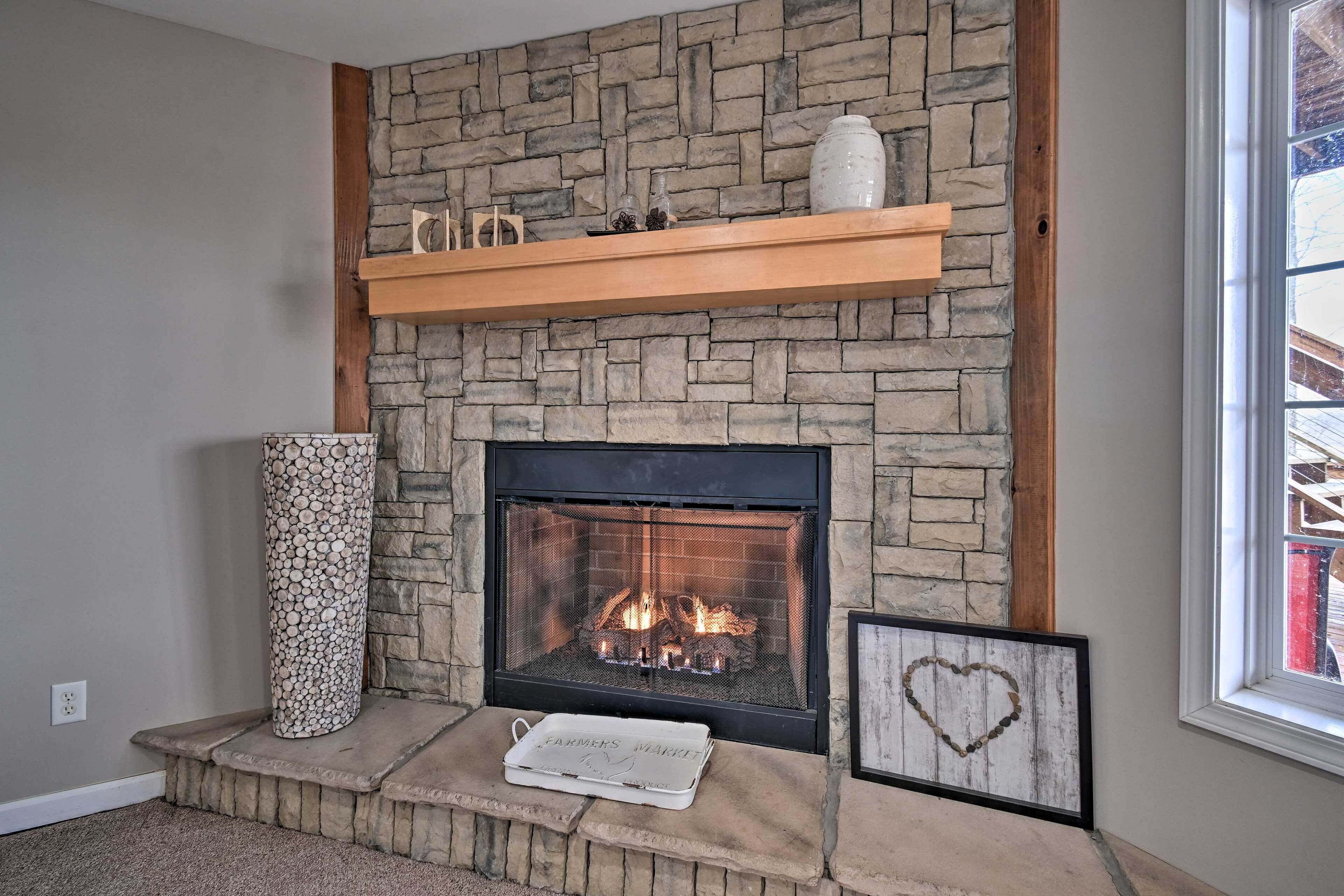 A fireplace with a stone facade, a wooden shelf above, and a framed picture below.