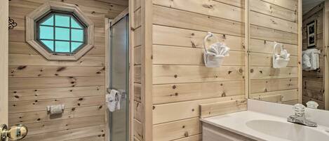 Un baño con paneles de madera, un espejo grande, un lavabo y una ducha.