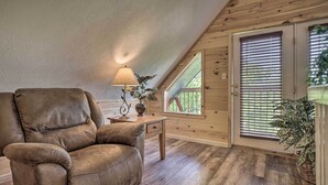 A cozy room with a leather recliner, a small table with a lamp, and a window with blinds. - Hot Tub & Private Deck: Rustic Pigeon Forge Cabin (Pigeon Forge)