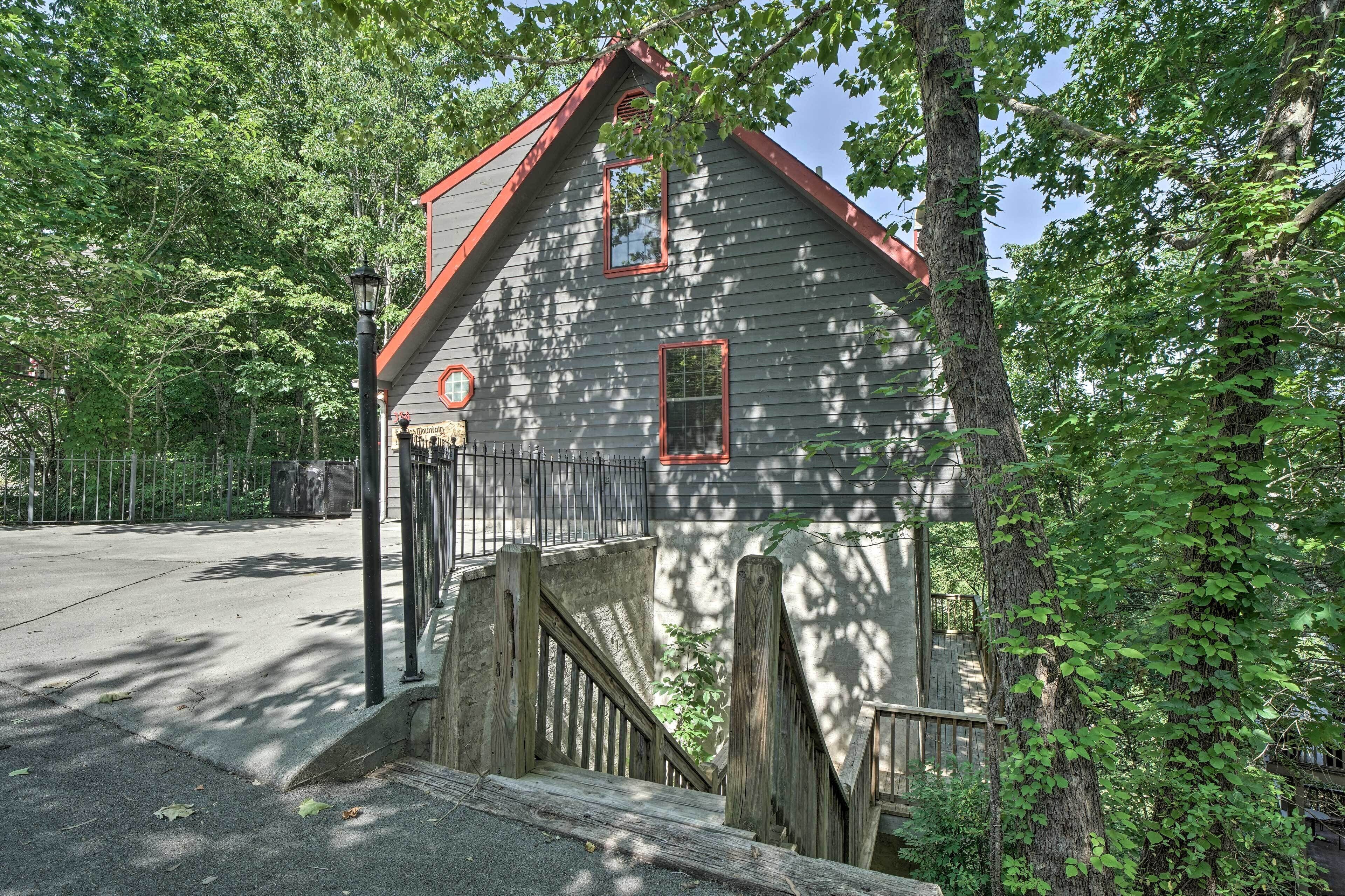 A small, rustic cabin with a steep wooden staircase, surrounded by lush greenery.