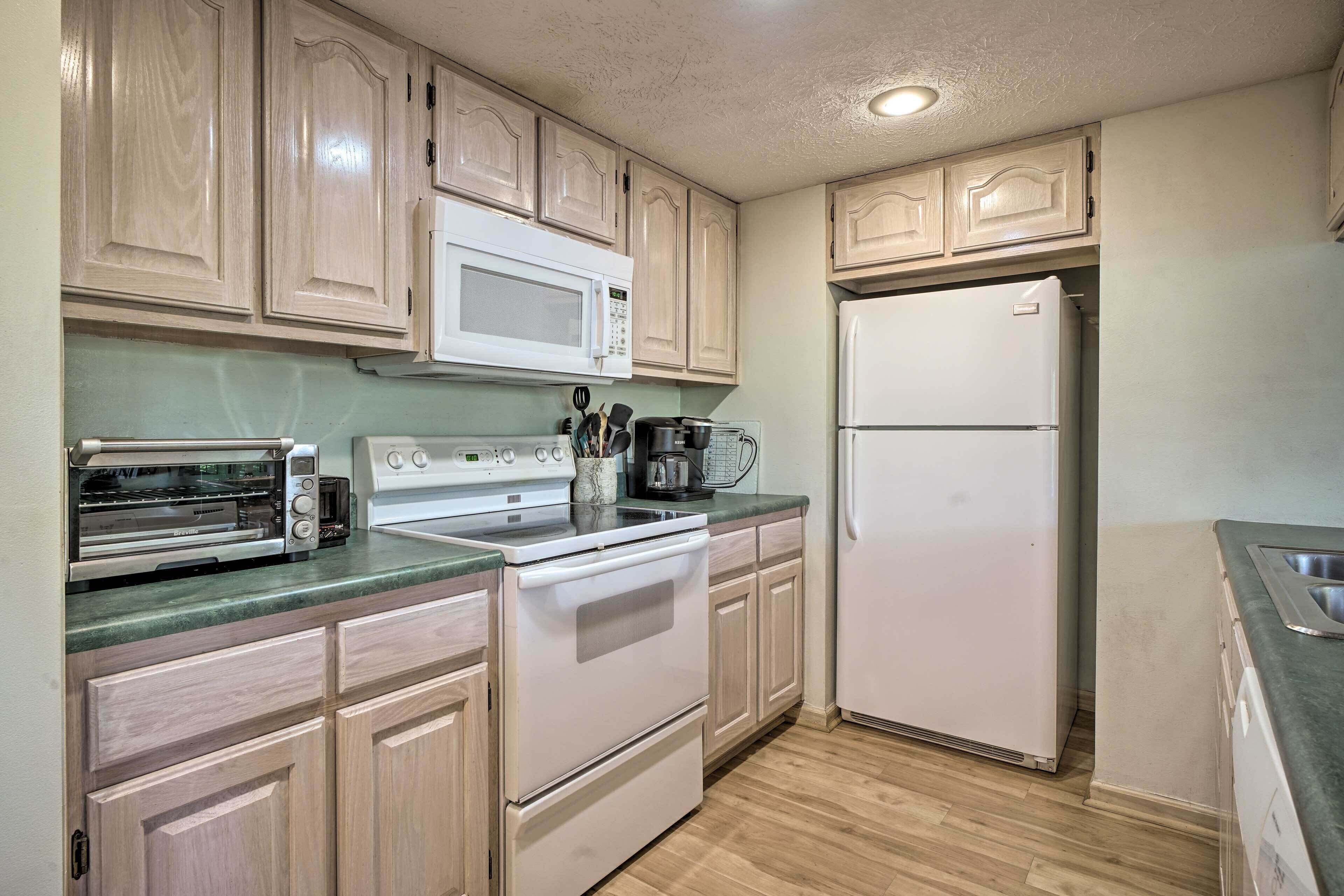 A kitchen with wooden cabinets, a microwave, a stove, a refrigerator, and a sink.