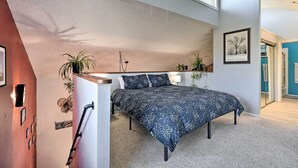 Une chambre à coucher avec un lit, un bureau et une chaise. Il y a des plantes sur le bureau et un tableau au mur.