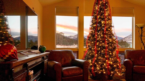 A cozy living room with a large Christmas tree, leather armchairs, a fireplace, and a view of a snowy landscape through the windows. - 3 Mi to Rmnp! Mtn-view Retreat in Estes Park (Estes Park)