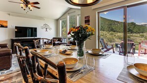 A dining area with a wooden table set for a meal, surrounded by chairs, a television, and a ceiling fan. - 3 Mi to Rmnp! Mtn-view Retreat in Estes Park (Estes Park)
