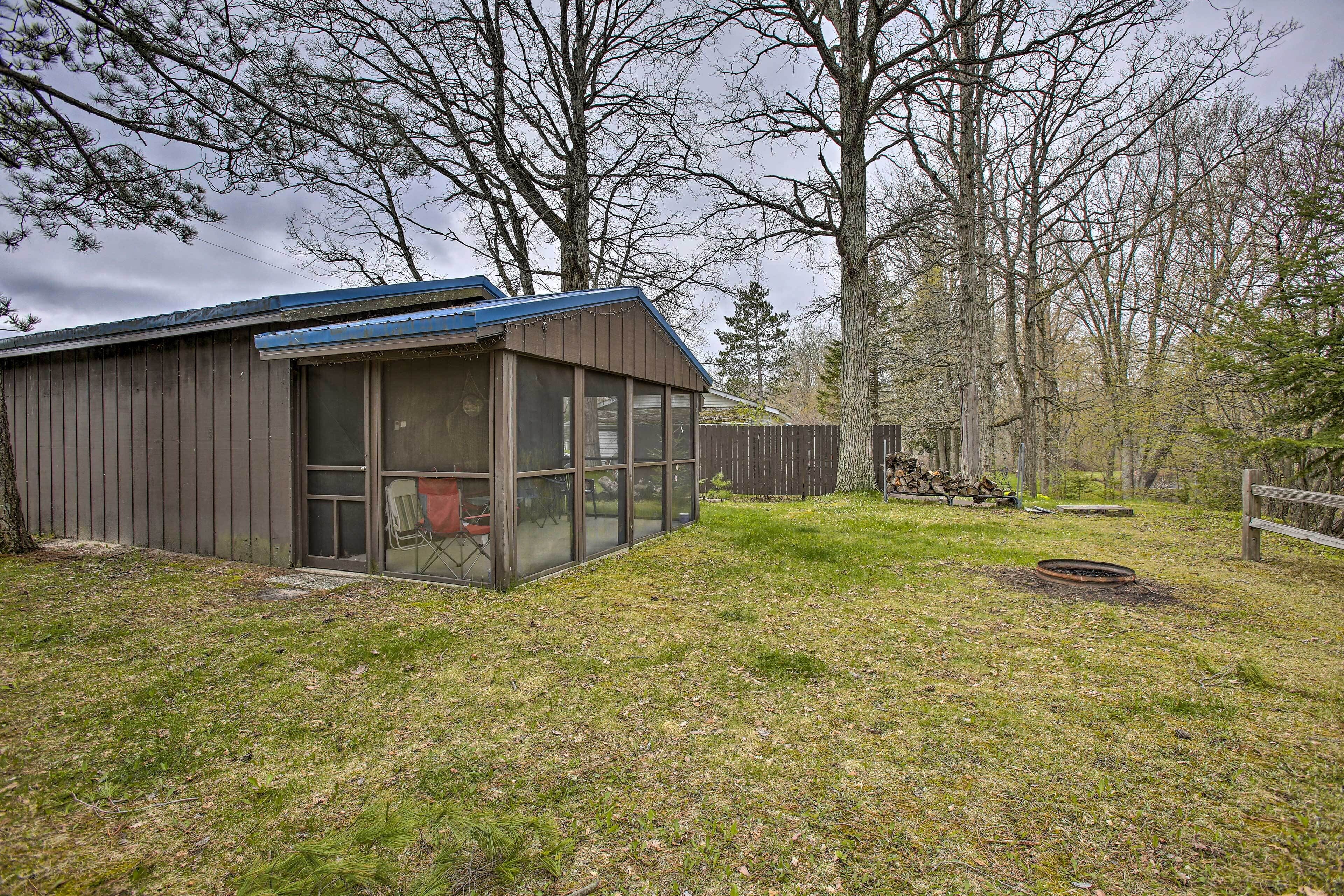 A small, single-story building with a glass door and windows, surrounded by a grassy yard and trees.