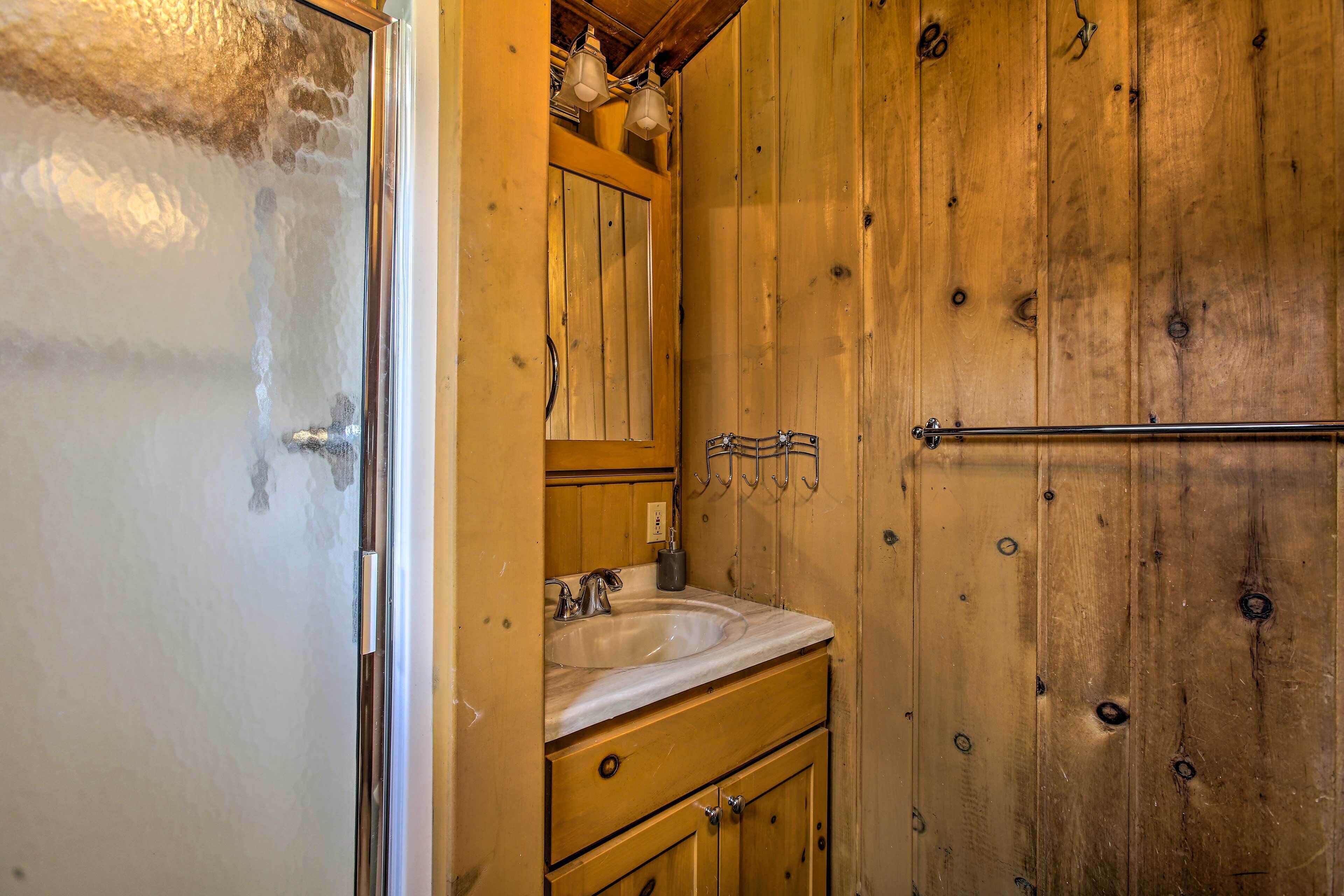 A wooden bathroom with a sink, mirror, and towel rack.