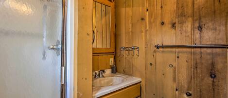 A wooden bathroom with a sink, mirror, and towel rack.