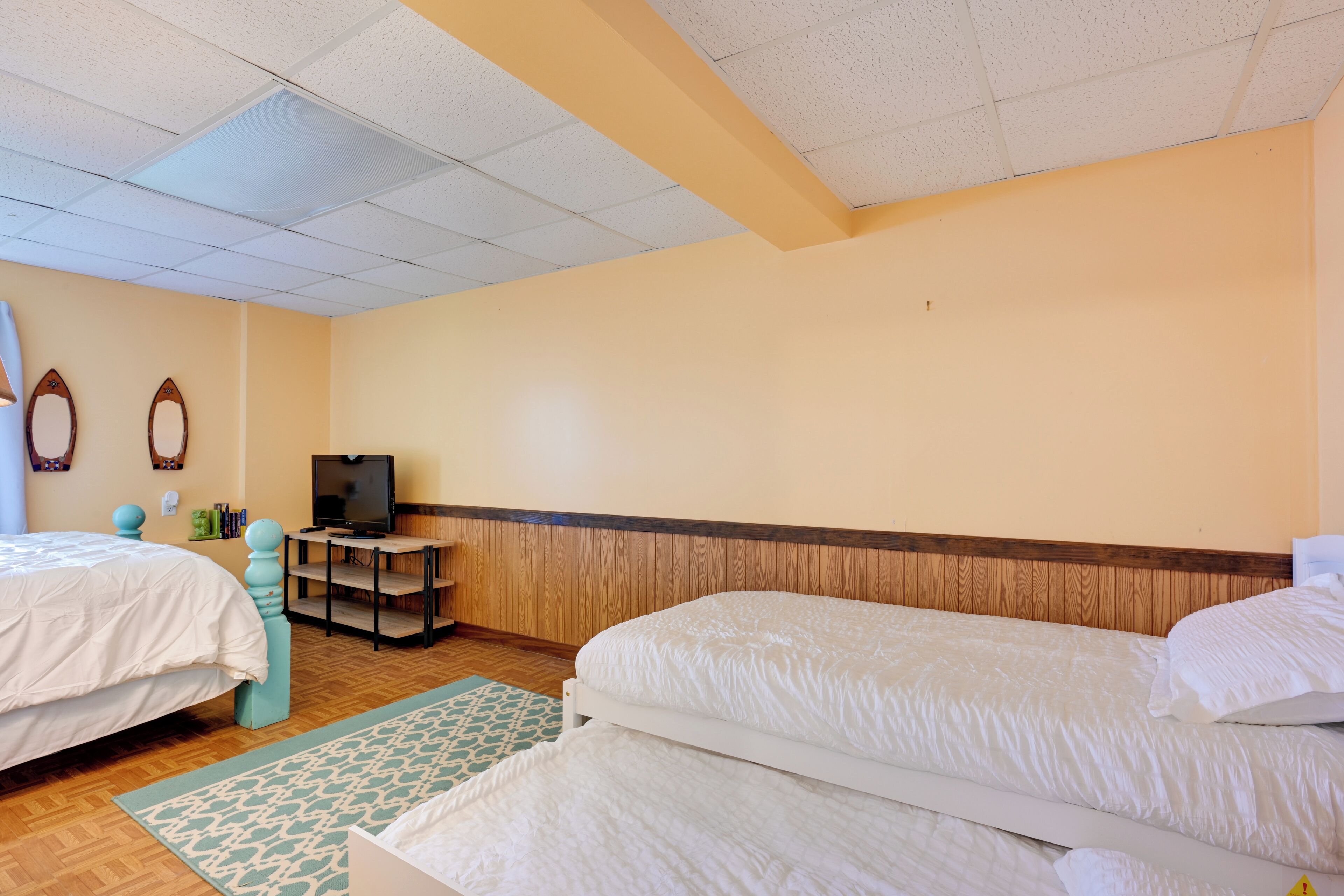 A hotel room with two beds, a television, and a wooden headboard.