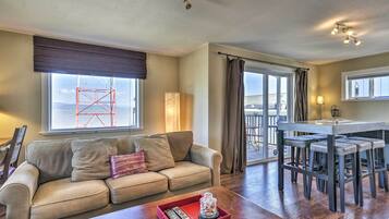 A living room with a sofa, a coffee table with a tray, a dining area with a table and chairs, and a view of the outside.