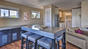 A modern kitchen with a central island, bar stools, and a refrigerator. - Waterfront Condo on Pier in Downtown Astoria! (Astoria)