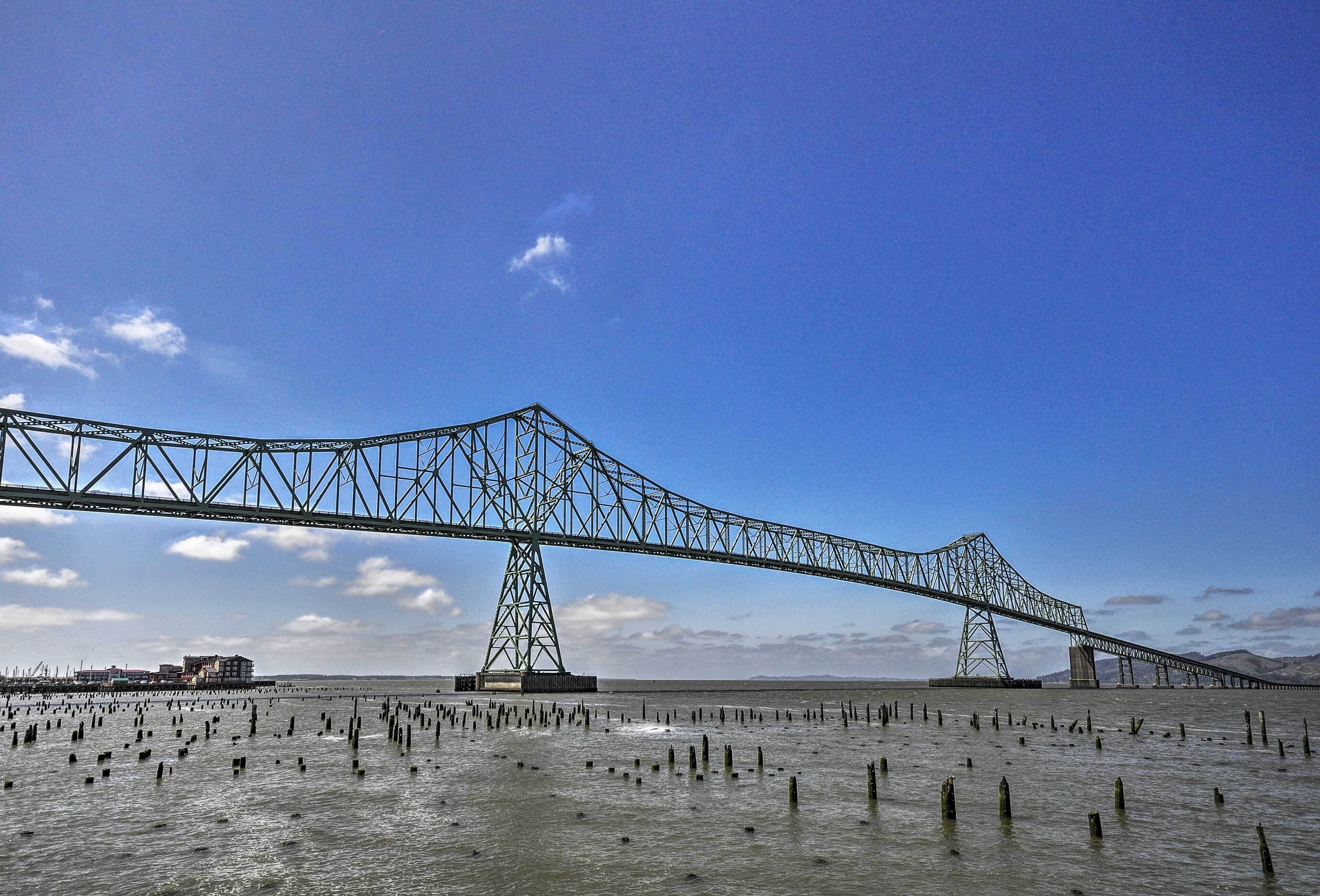 Un grand pont d’acier enjambant une étendue d’eau, avec un ciel dégagé.