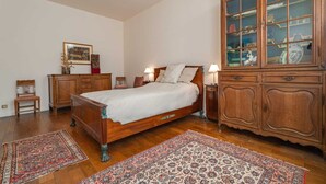 A bedroom with a wooden bed, a cabinet with glass doors, and two rugs on the floor. - Room of Puebla (Brugge)