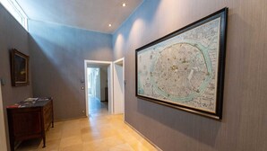 A hallway with a large framed map on the wall, a wooden dresser, and a door leading to another room. - Room of Puebla (Brugge)