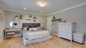 A bedroom with a bed, bedside table, dresser, and a mirror.