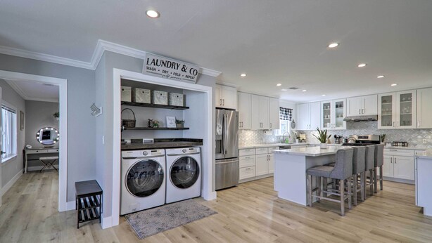 A modern kitchen with a laundry area, stainless steel appliances, and a bar seating area.