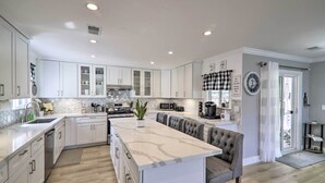 A modern kitchen with white cabinetry, a marble island, and a built-in oven.