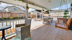 A covered outdoor patio with wicker furniture, a swing, and hanging planters.