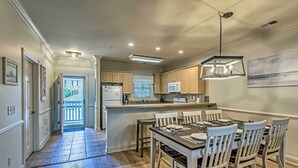 A modern kitchen with a central island, wooden chairs, and a dining table. - 3 Mi to Myrtle Beach: Coastal Condo w/ Pool! (Myrtle Beach)