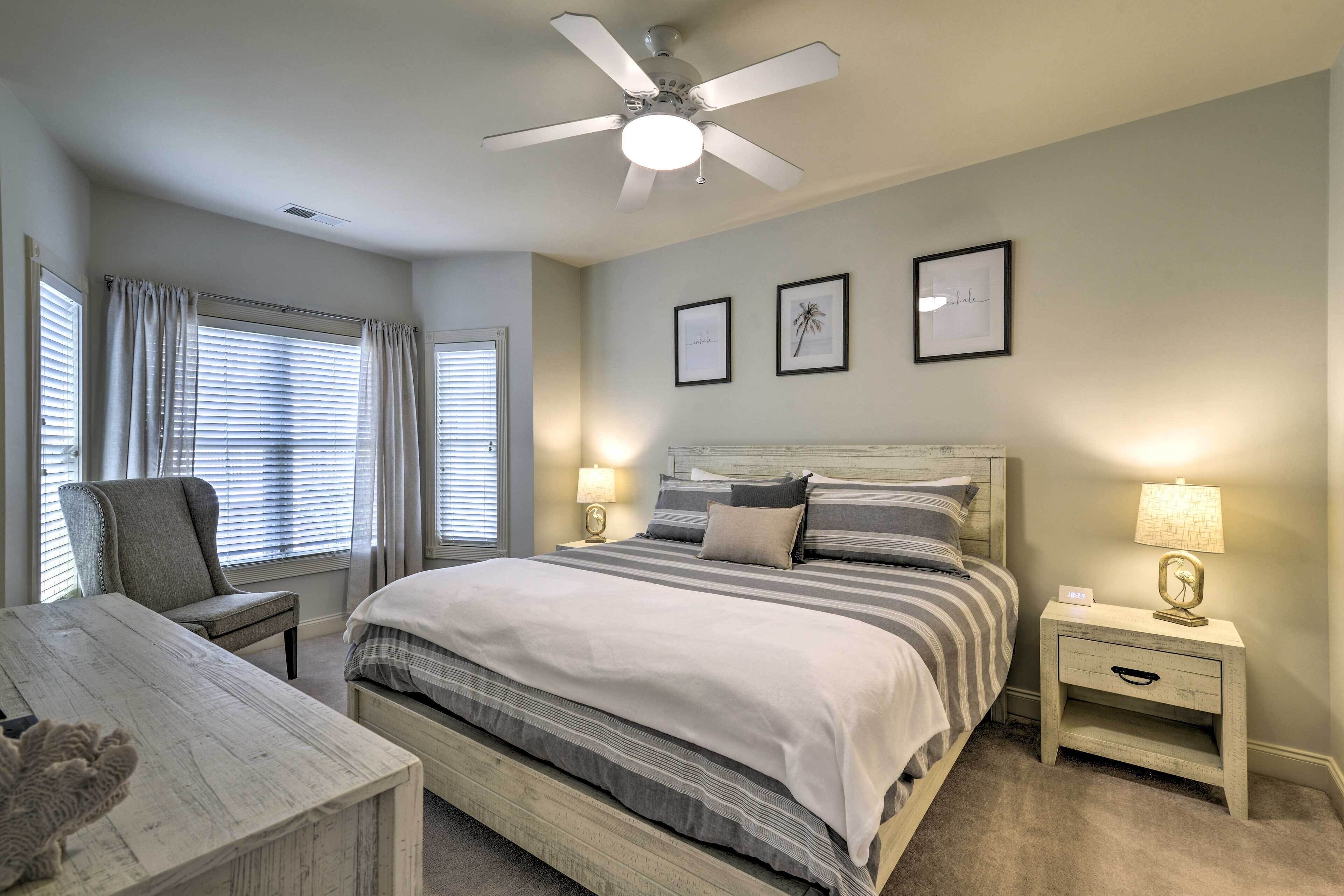A bedroom with a bed, nightstands, a chair, a desk, and a ceiling fan.