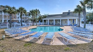 A pool area with lounge chairs arranged around it, a covered seating area, and a building with a white facade and columns. - 3 Mi to Myrtle Beach: Coastal Condo w/ Pool! (Myrtle Beach)