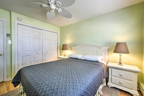 A bedroom with a bed, two bedside tables with lamps, a ceiling fan, and a white door. - Wildwood Crest Condo: 2 Blocks to Beach! (Wildwood Crest)