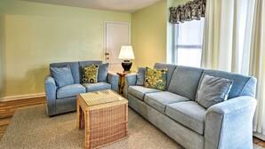 Ein Wohnzimmer mit zwei hellblauen Sofas, einem Korbtisch und einer Lampe auf einem Beistelltisch.