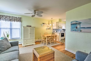 A living room with a sofa, a coffee table, and a dining area with chairs and a table. There is a kitchen in the background with a microwave and a refrigerator. - Wildwood Crest Condo: 2 Blocks to Beach! (Wildwood Crest)