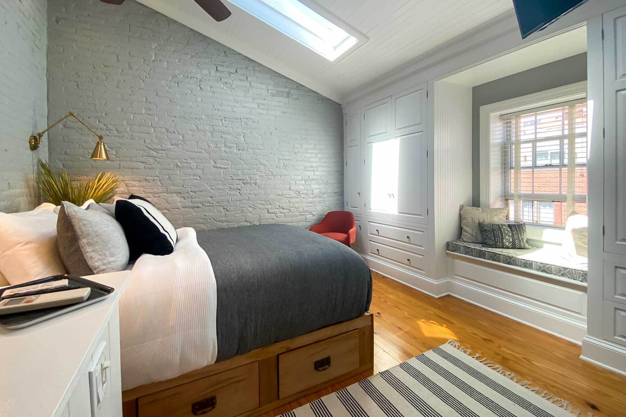 Een slaapkamer met een hoogslaper, een raamzitje en een bakstenen muur.