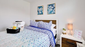 A neatly made bed with a patterned blue and white bedspread, a bedside table with a lamp, and a welcome sign. - Philly Hub Near Intl Soccer, Downtown Attractions (Philadelphia)