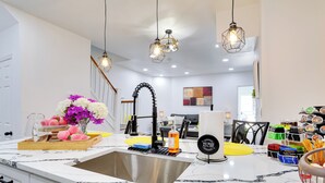 A modern kitchen with a marble countertop, a stainless steel sink, and hanging pendant lights. - Philly Hub Near Intl Soccer, Downtown Attractions (Philadelphia)