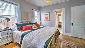 Quarto com cama, mesa de cabeceira, abajur e vista para o exterior.