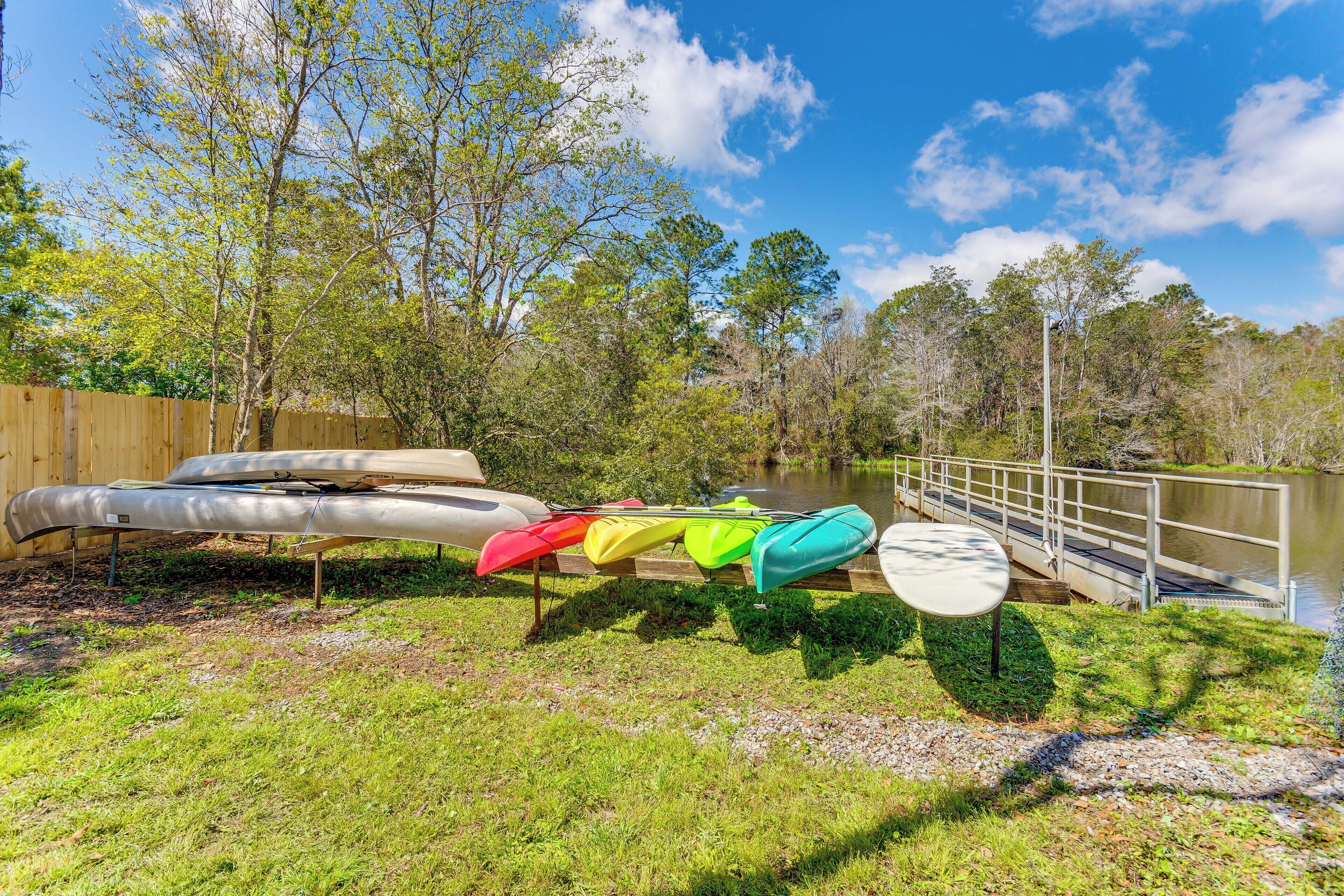 A grassy area with kayaks and a wooden fence.