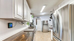 A kitchen with white cabinets, a wooden countertop, stainless steel appliances, and a tiled floor.