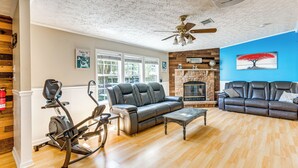 A living room with a fireplace, two sofas, a coffee table, and exercise equipment.