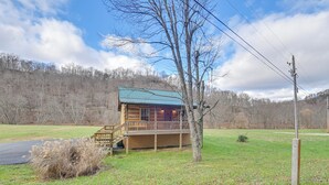 A cabin with a wooden exterior, a metal roof, and a deck. - Pet-friendly Cabin w/ Hot Tub in Daniel Boone NF (Beattyville)