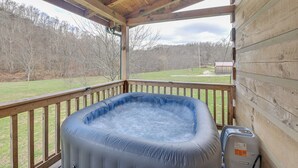 A hot tub on a wooden deck with a view of a grassy yard and trees. - Pet-friendly Cabin w/ Hot Tub in Daniel Boone NF (Beattyville)